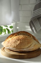 Photo of Freshly baked sourdough bread on white wooden table indoors