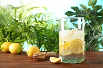 Natural lemonade in pitcher on wooden table