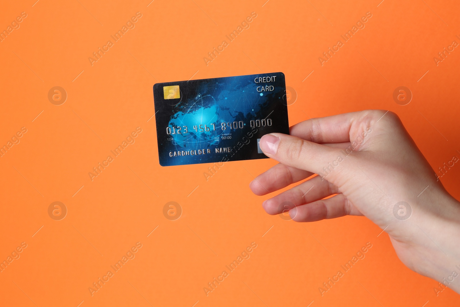 Photo of Woman holding credit card on orange background, closeup