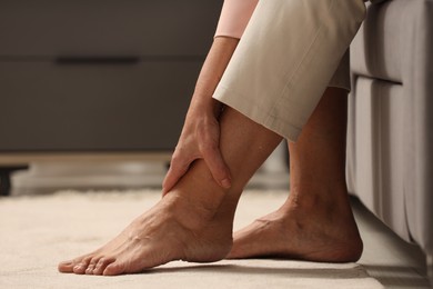 Photo of Mature woman suffering from pain in leg indoors, closeup. Rheumatism symptom