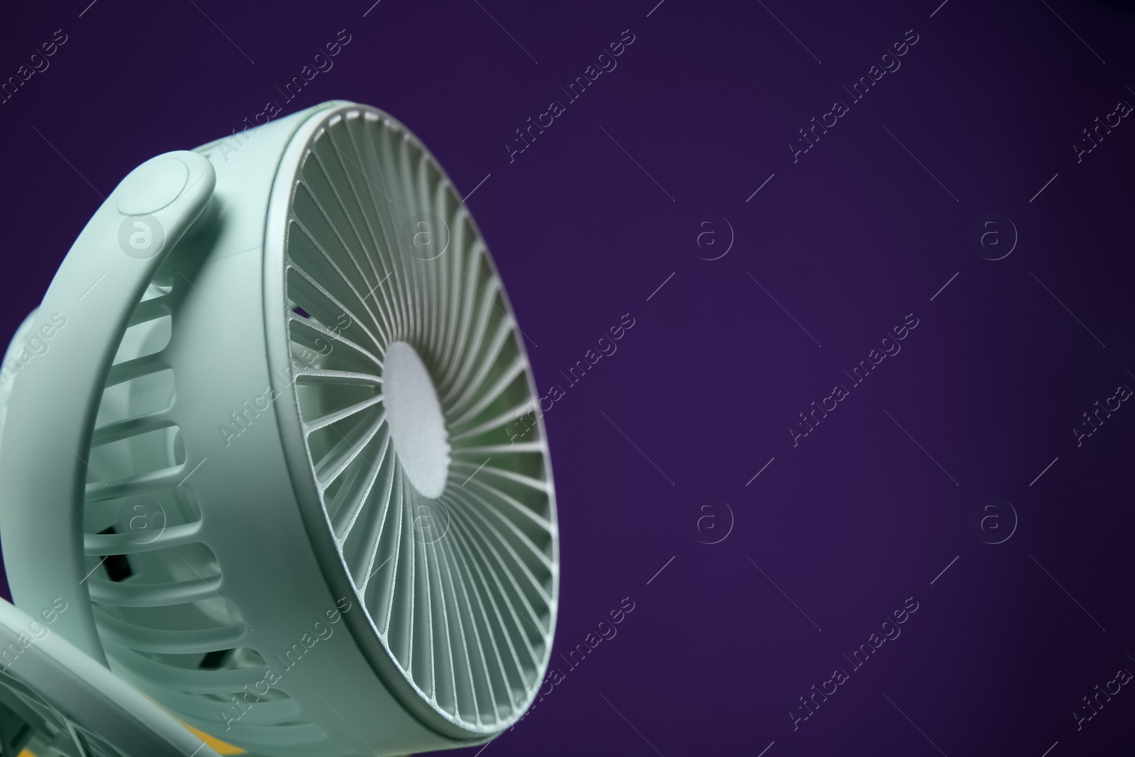 Photo of Modern electric fan on violet background, closeup. Space for text