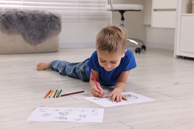 Photo of Cute little boy coloring on warm floor at home. Heating system