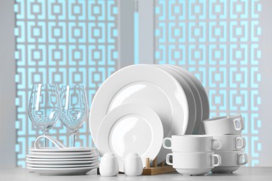 Photo of Set of clean dishware and glasses on light grey table