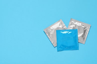 Condom packages on light blue background, flat lay and space for text. Safe sex