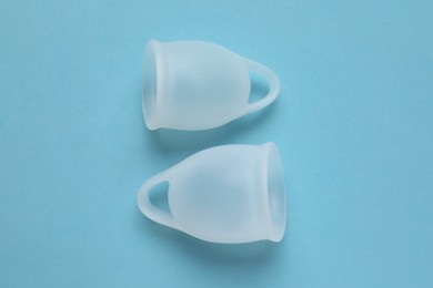 Menstrual cups on light blue background flat lay. Reusable female hygiene product