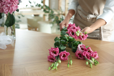 Photo of Florist making beautiful bouquet at table in workshop, closeup