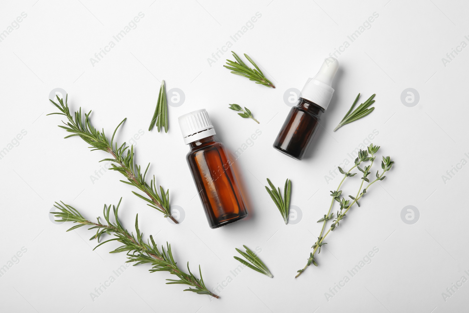 Photo of Composition with different bottles of rosemary oil on white background, top view