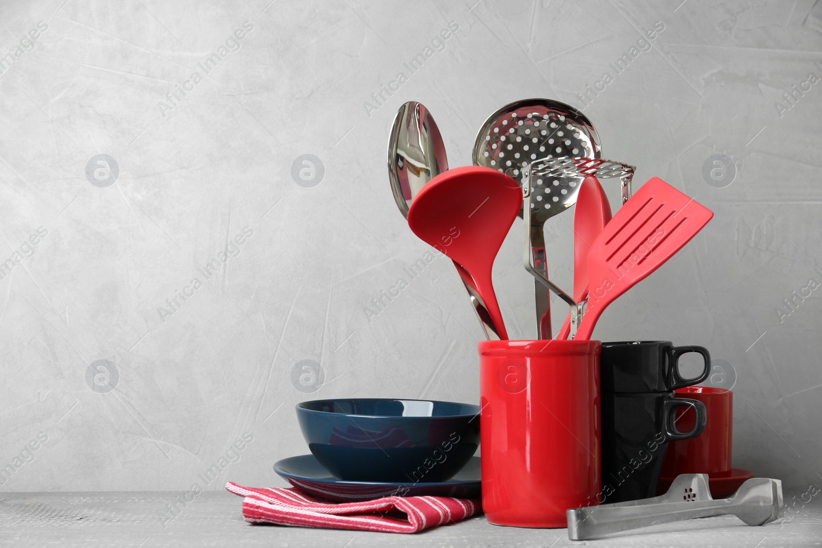 Photo of Different kitchen utensils on wooden table against light grey background. Space for text