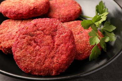 Delicious beetroot cutlets and parsley in black bowl, closeup. Vegan dish