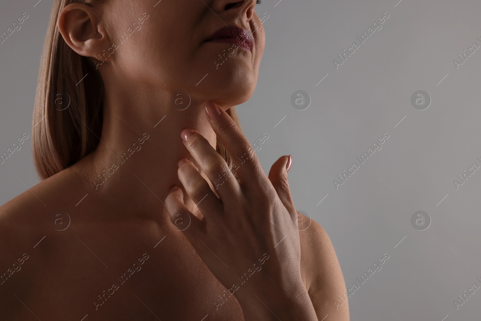 Photo of Woman touching her neck on grey background, closeup