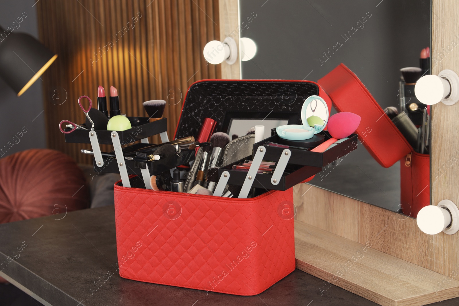 Photo of Beautician case with professional makeup products and tools on dressing table