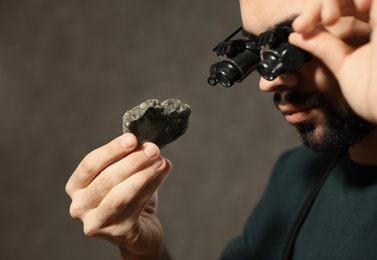 Photo of Male jeweler evaluating semi precious gemstone in workshop, closeup