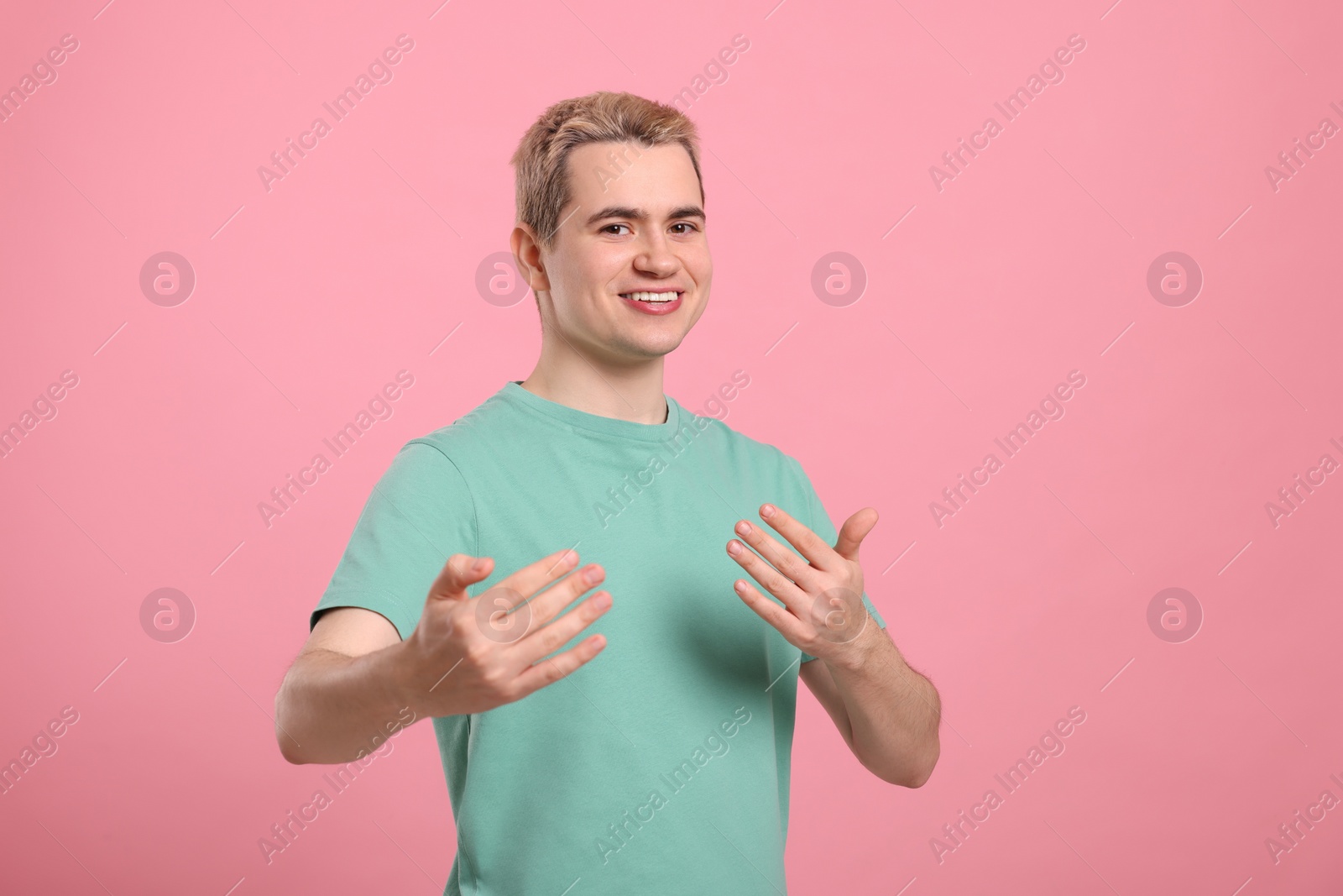 Photo of Happy man inviting to come in against pink background