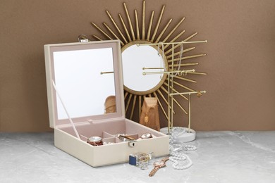 Photo of Jewelry box with many different accessories, perfume, stand and decor on light grey table