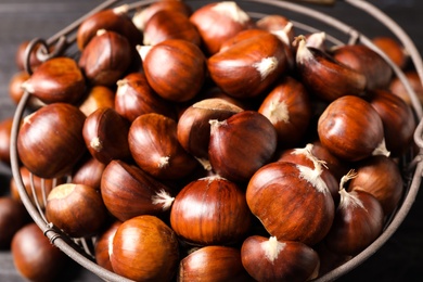 Photo of Fresh sweet edible chestnuts in basket, closeup