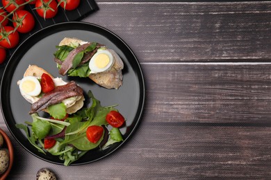 Photo of Delicious bruschettas with anchovies, cream cheese, eggs and tomatoes on wooden table, flat lay. Space for text