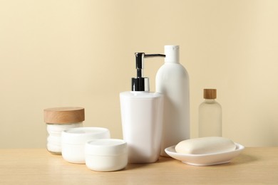 Photo of Different bath accessories on wooden table against beige background