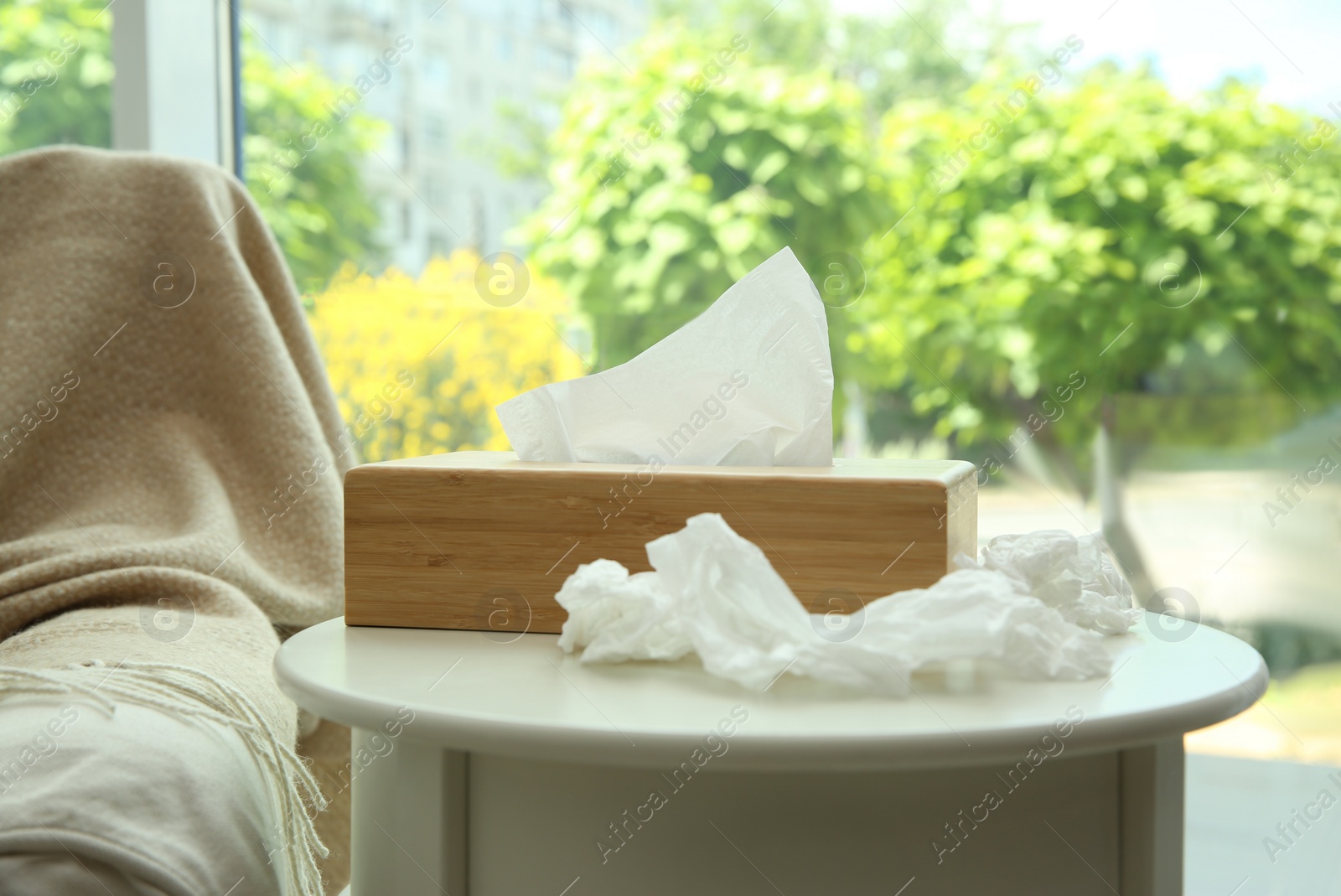 Photo of Used paper tissues and wooden holder on white table