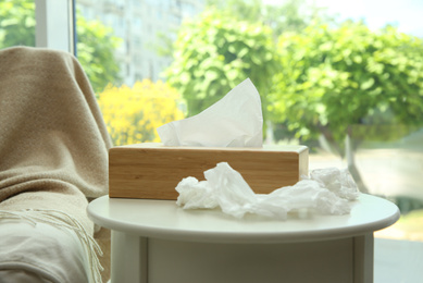 Photo of Used paper tissues and wooden holder on white table