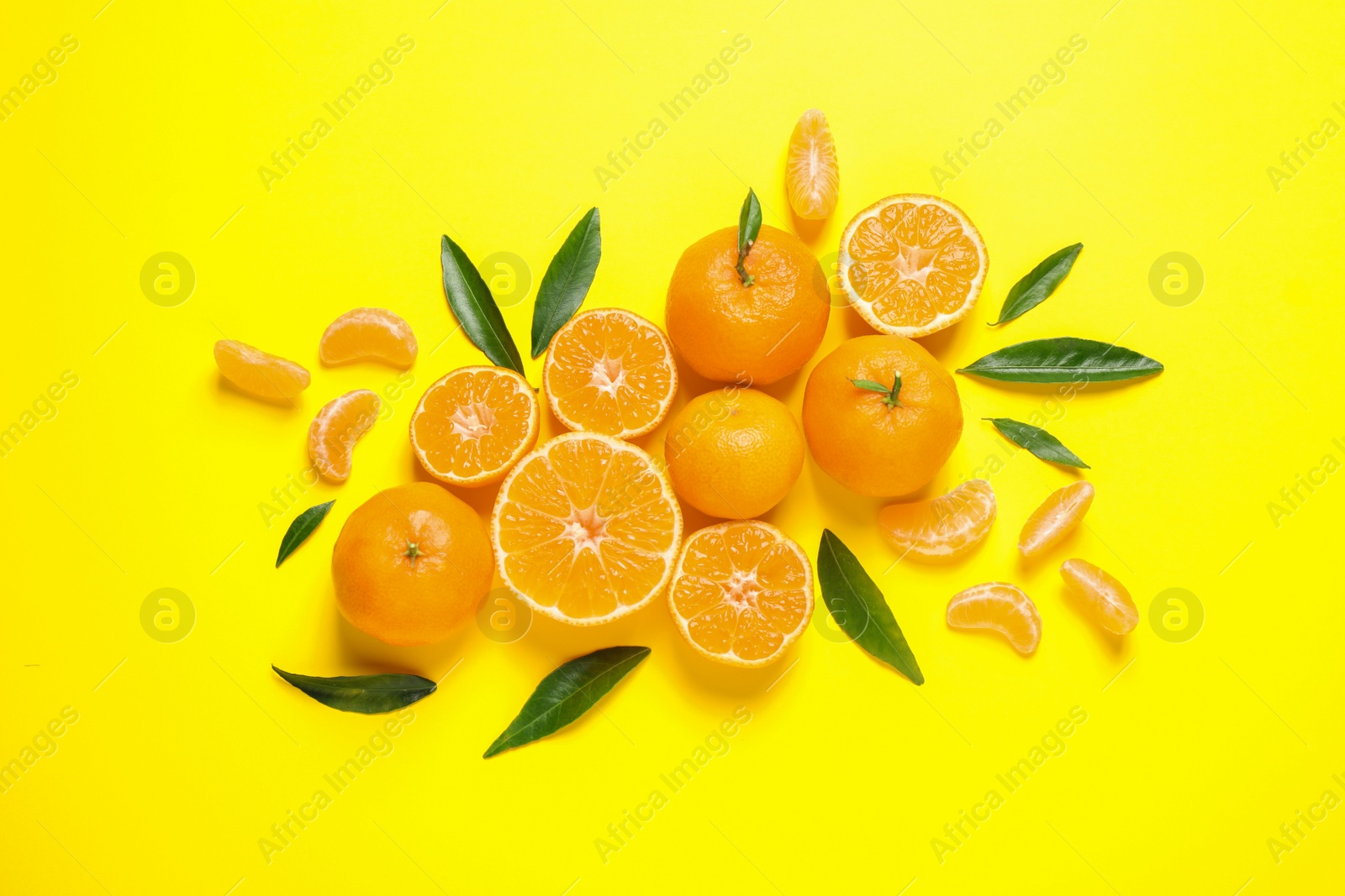 Photo of Flat lay composition with fresh ripe tangerines and leaves on yellow background. Citrus fruit