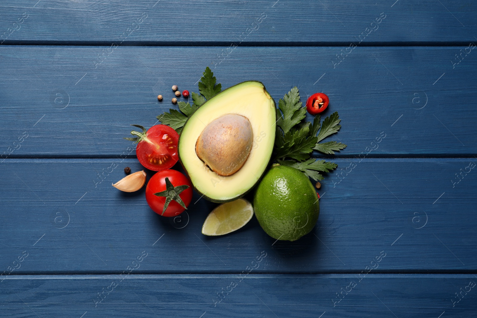 Photo of Fresh ingredients for guacamole on blue wooden table, flat lay