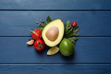 Fresh ingredients for guacamole on blue wooden table, flat lay