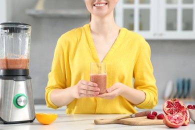 Photo of Woman with delicious smoothie in kitchen, closeup