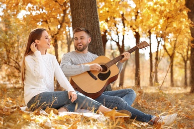 Photo of Young couple with guitar in autumn park