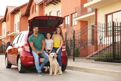 Photo of Happy family with dog near car on street