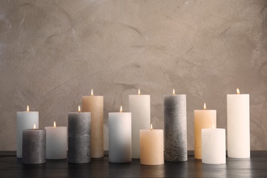 Photo of Burning candles on table against color background