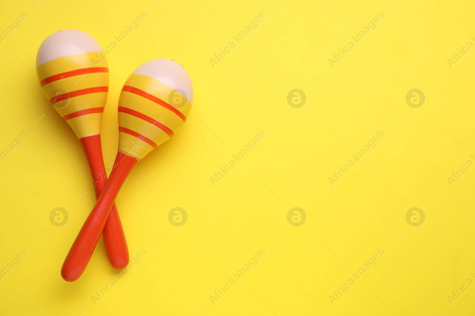 Photo of Colorful maracas on yellow background, flat lay with space for text. Musical instrument