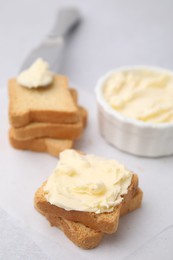 Slices of bread with tasty butter on light table, closeup