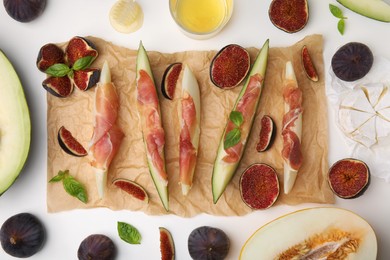 Photo of Tasty melon, jamon and figs served on white table, flat lay