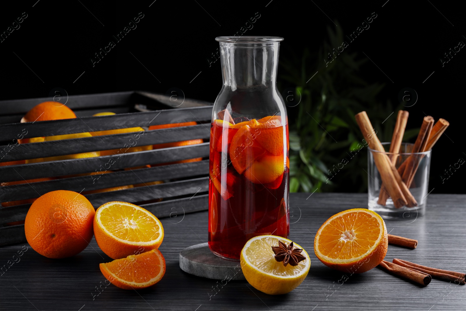 Photo of Aromatic punch drink and ingredients on black table