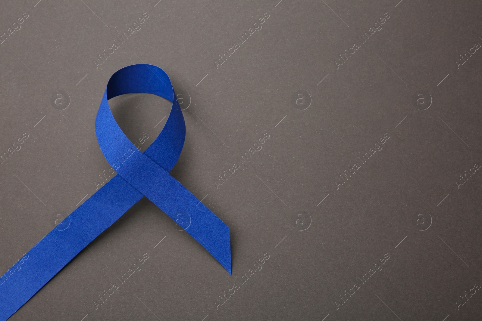 Photo of Blue ribbon on grey background, top view with space for text. Symbol of social and medical issues