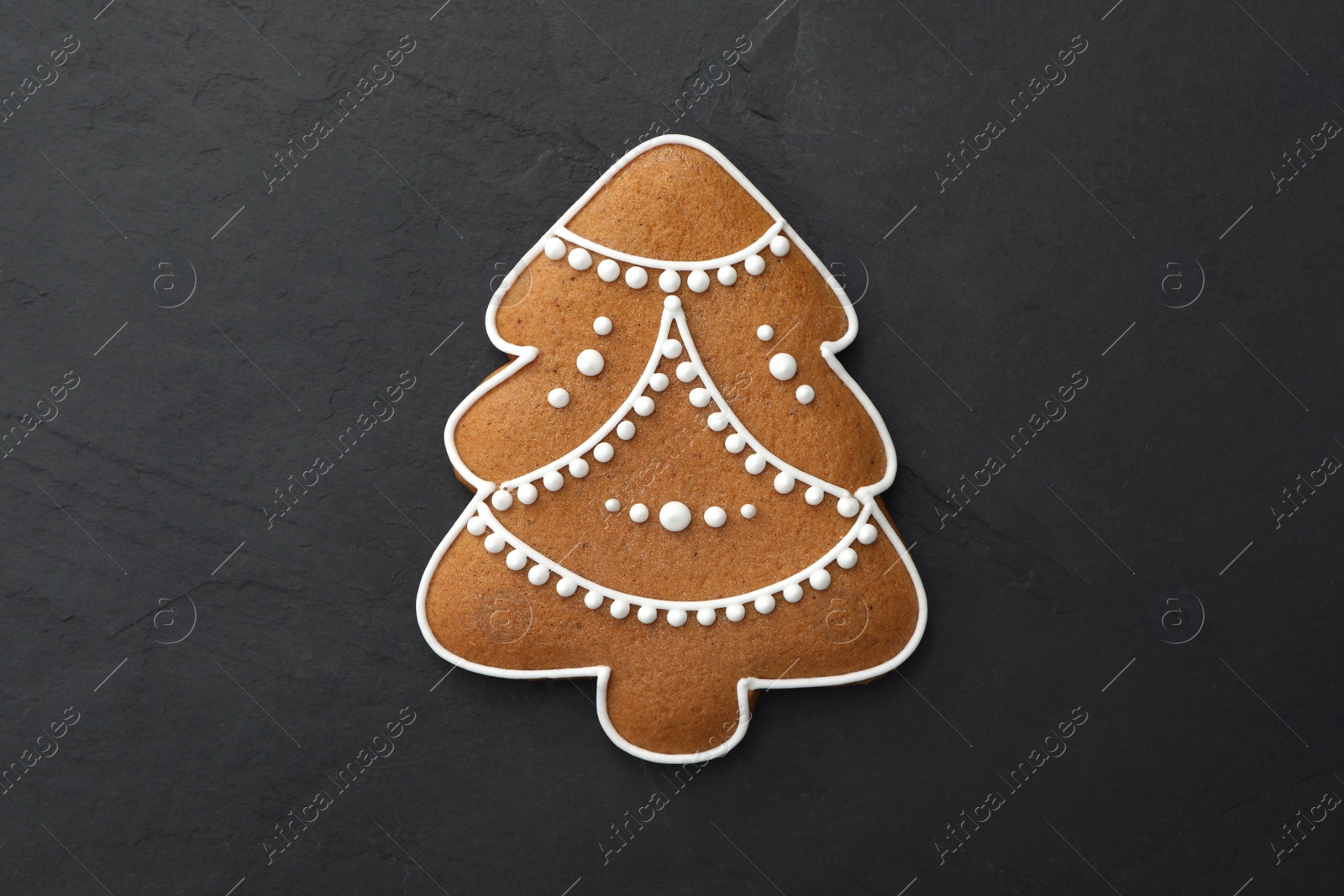 Photo of Christmas tree shaped cookie on black table, top view