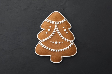 Photo of Christmas tree shaped cookie on black table, top view