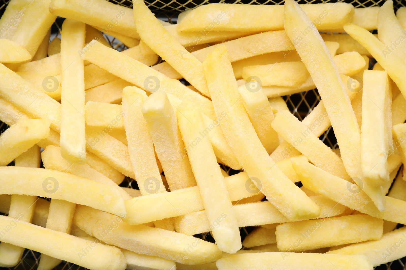 Photo of Uncooked french fries in metal basket, closeup