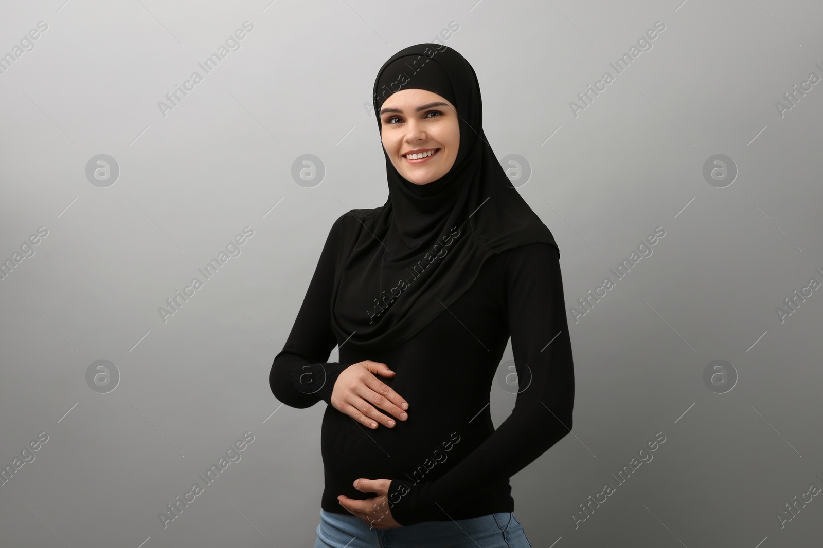 Photo of Portrait of pregnant Muslim woman in hijab on light gray background