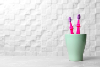 Baby toothbrushes in holder on table near light wall with space for text