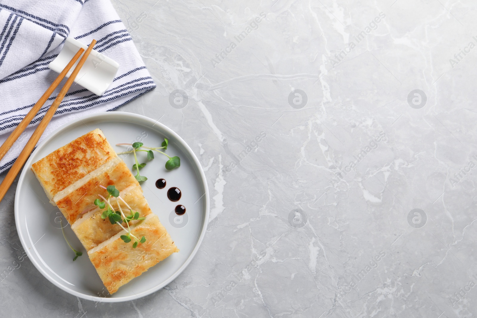 Photo of Delicious turnip cake with microgreens served on grey table, flat lay. Space for text