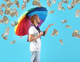 Image of Man with rainbow umbrella under money rain on color background 