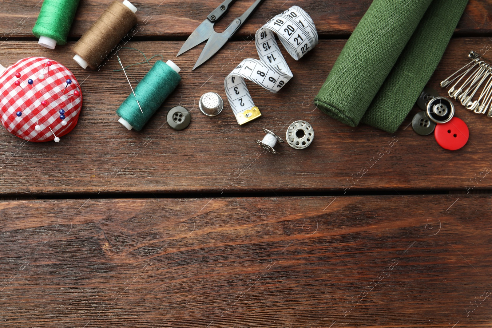 Photo of Threads and other sewing supplies on wooden table, flat lay. Space for text