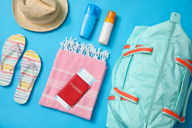 Photo of Flat lay composition with bag and travel accessories on blue background