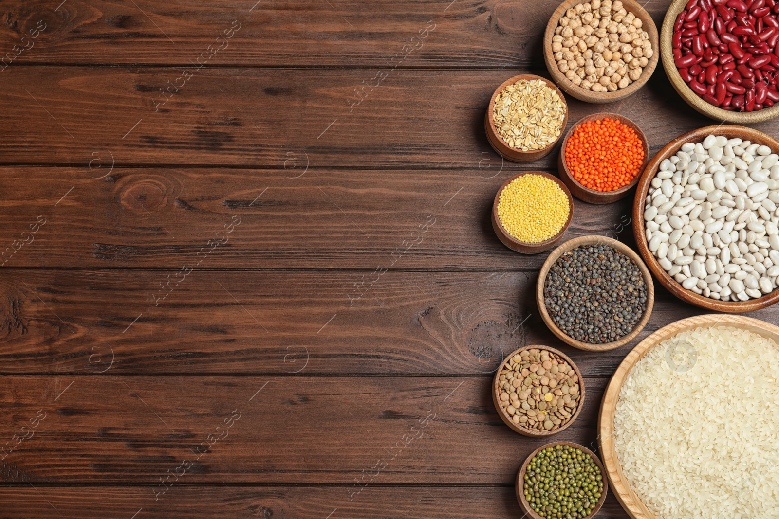 Photo of Flat lay composition with different types of legumes and cereals on wooden table, space for text. Organic grains