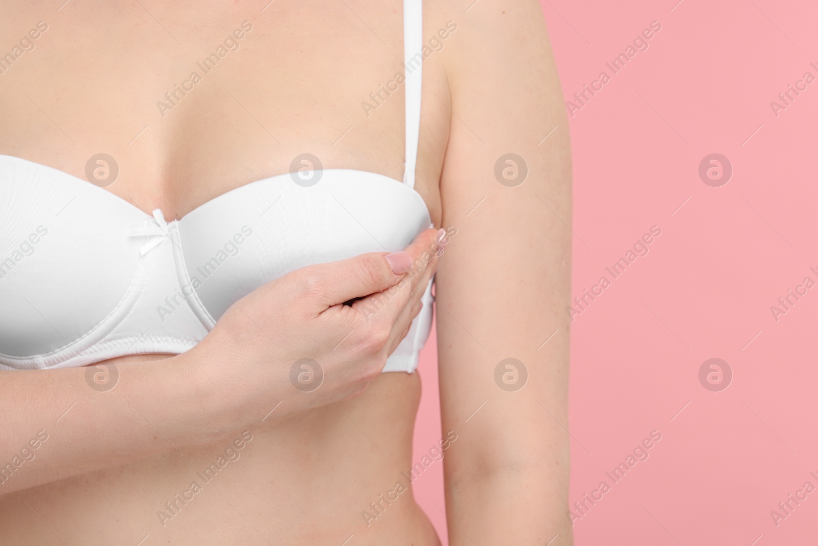 Photo of Mammology. Young woman doing breast self-examination on pink background, closeup. Space for text