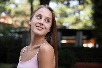 Portrait of beautiful young woman in park, space for text