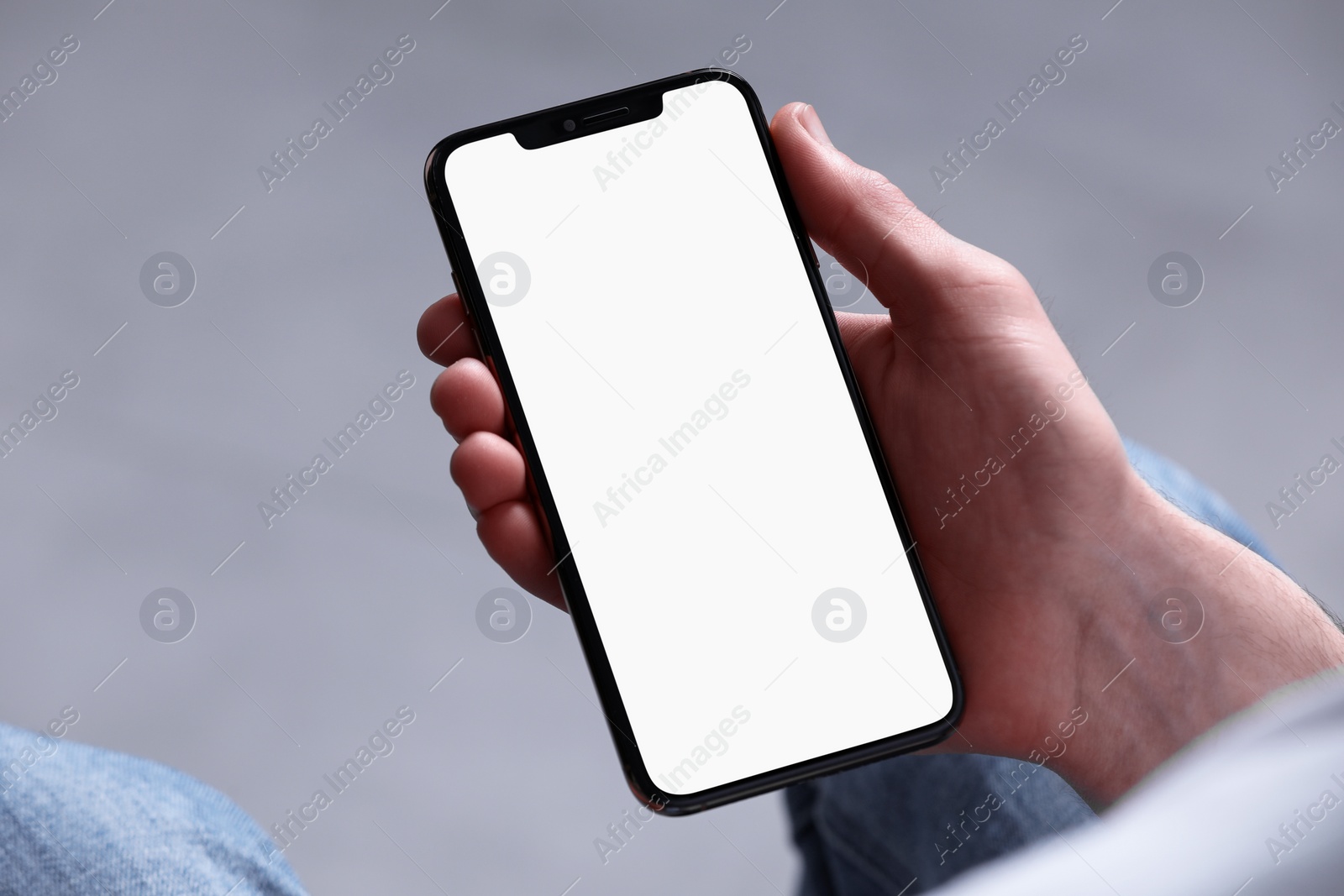 Photo of Man holding smartphone with blank screen on light grey background, closeup. Mockup for design