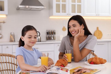 Photo of Happy mother and daughter having breakfast together in kitchen. Single parenting