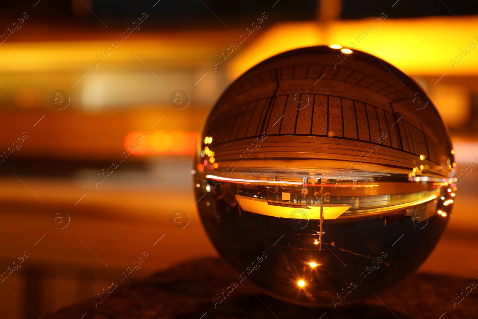 Photo of Beautiful city street, overturned reflection. Crystal ball at night, closeup. Space for text